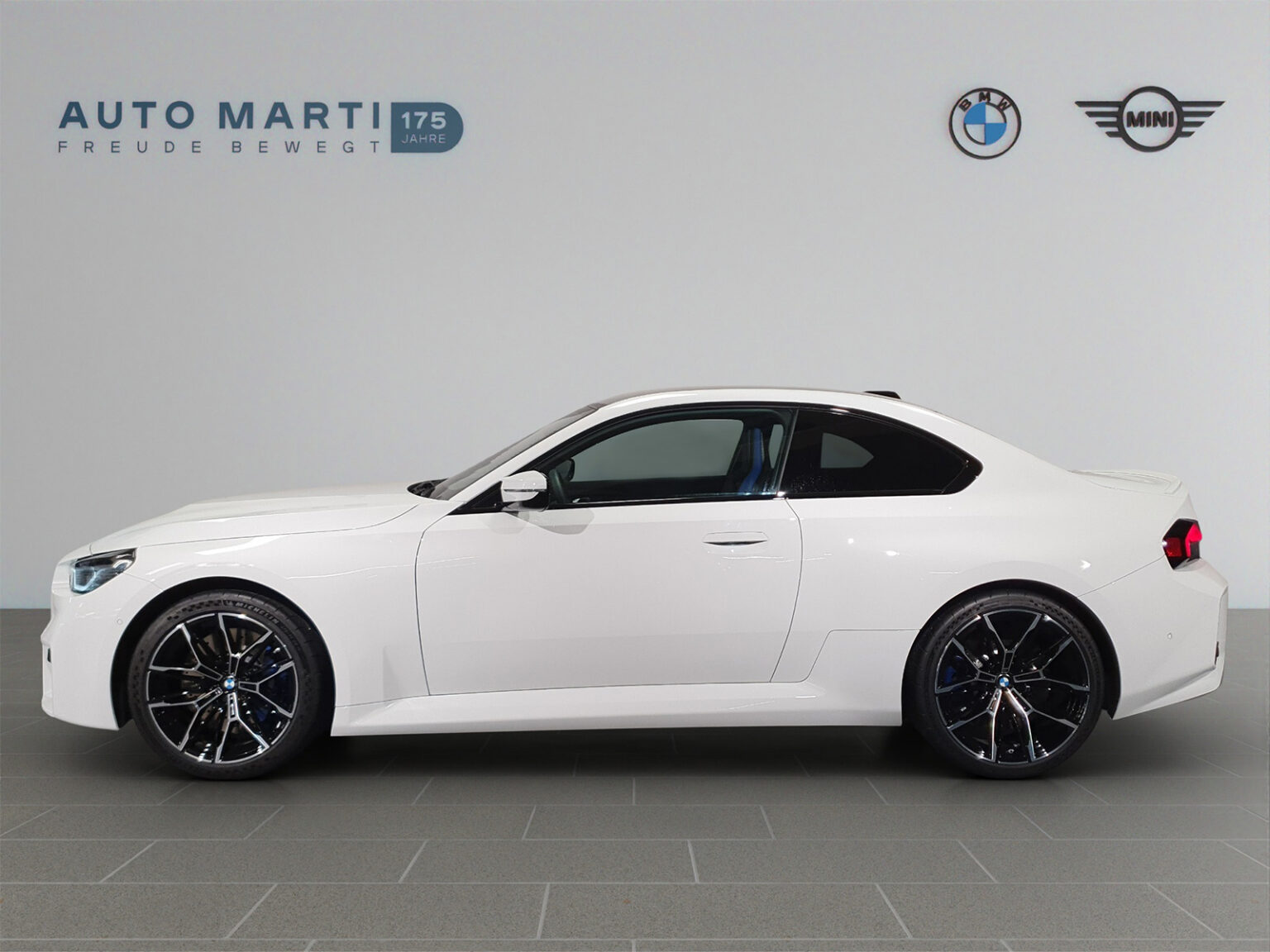 White BMW photographed in a branded dealer studio